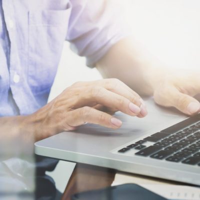 Man's hands typing on laptop keyboard.