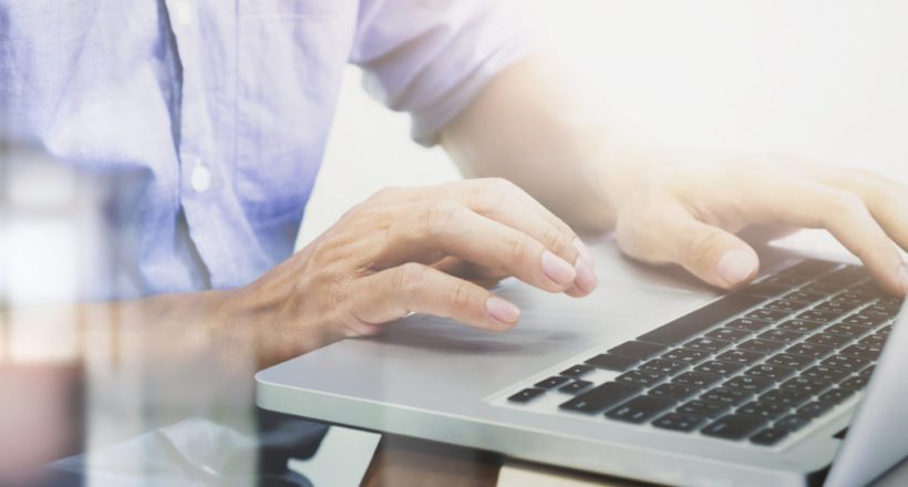 Man's hands typing on laptop keyboard.
