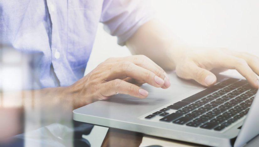 Man's hands typing on laptop keyboard.