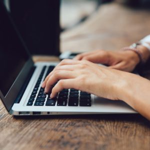 Close-up view of female hands typing on keyboard of laptop