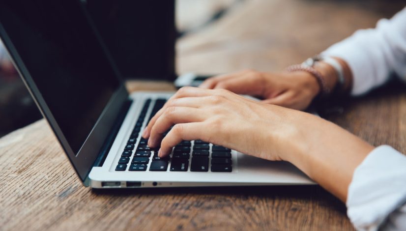 Close-up view of female hands typing on keyboard of laptop