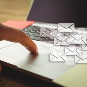 Composite image of hand using laptop put on a desk with letter icons