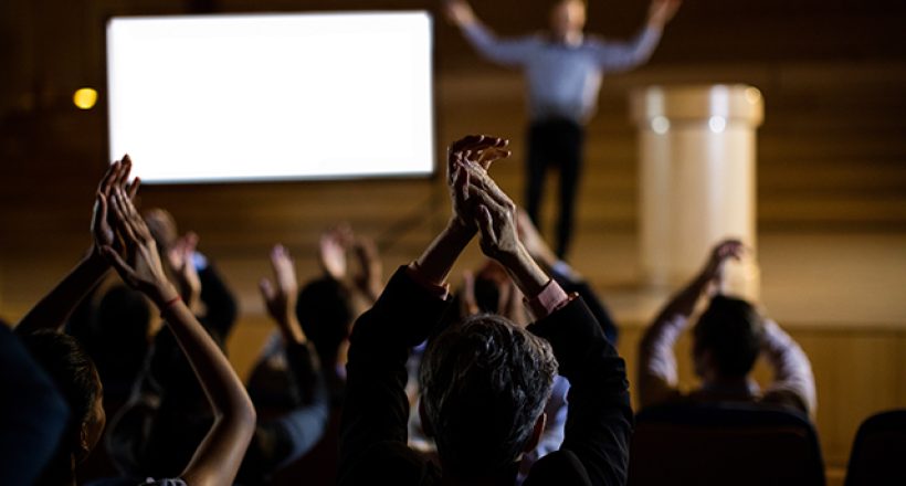 Audience applauding speaker after conference presentation at conference center