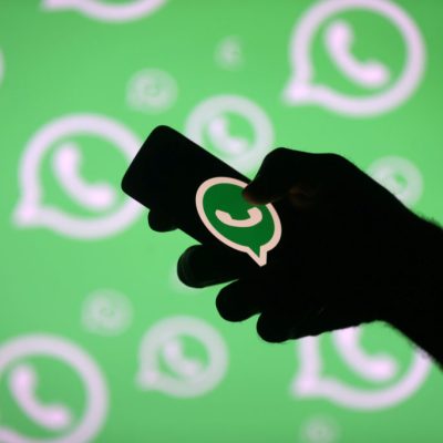 FILE PHOTO: A man poses with a smartphone in front of displayed Whatsapp logo in this illustration