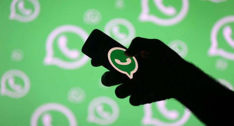 FILE PHOTO: A man poses with a smartphone in front of displayed Whatsapp logo in this illustration