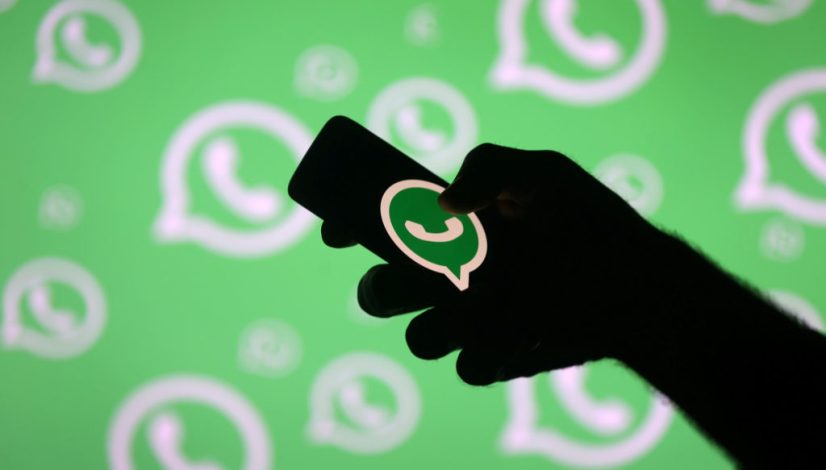 FILE PHOTO: A man poses with a smartphone in front of displayed Whatsapp logo in this illustration