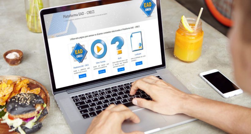 Young self-employed man working on his project on generic laptop while sitting at cafe and using free wi-fi. Male student browsing internet or checking email on electronic device during lunch